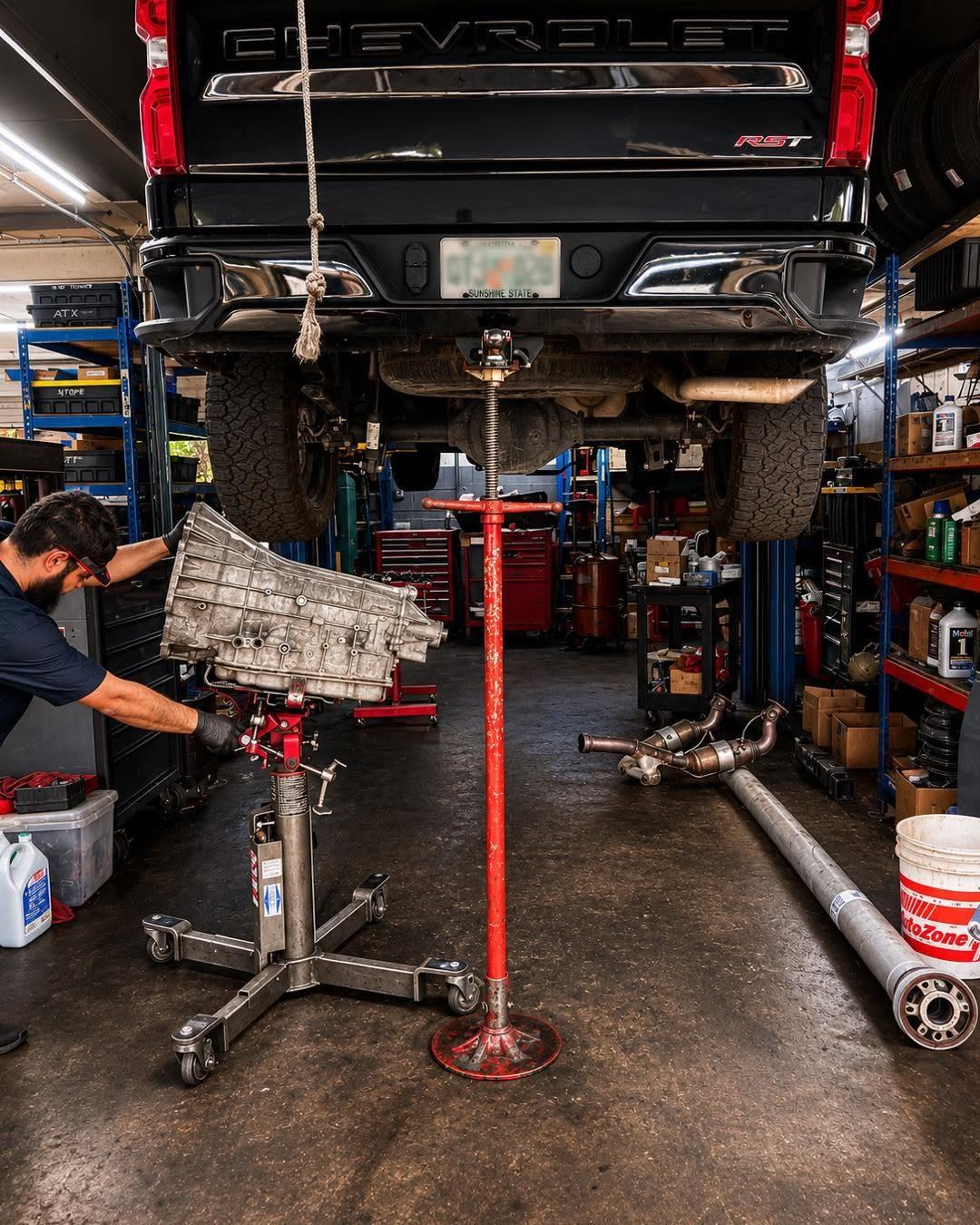 Technician lowering a transmission from a Silverado on a transmission jack